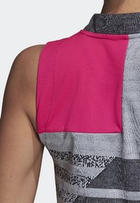 Haut de sport sans manches avec un panneau supérieur en maille rose et une section inférieure grise texturée à motifs avec des accents graphiques subtils.