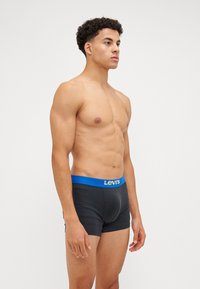 Boxer-briefs noirs avec une ceinture bleue portant le logo "Levi's" en doré. Le design est ajusté avec une texture lisse.