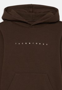 Rjava kapuca iz mešanice mehkega bombaža, ki ima kenguru žep in belo napis "JACK & JONES" čez prsi.