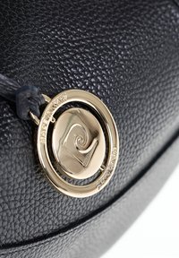 Borsa a tracolla in pelle nera con texture, dotata di un accento hardware circolare dorato con un design a spirale. La superficie è in rilievo e dettagliata.