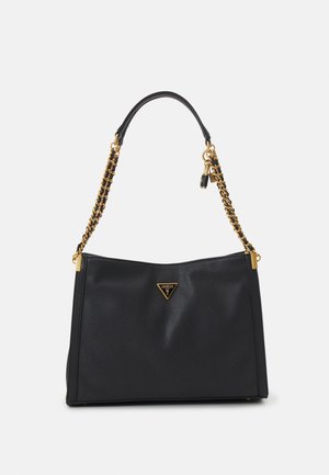 Sac à main en cuir noir avec bandoulière chaîne dorée, plaque triangulaire avec logo Guess et petit charm cadenas suspendu.