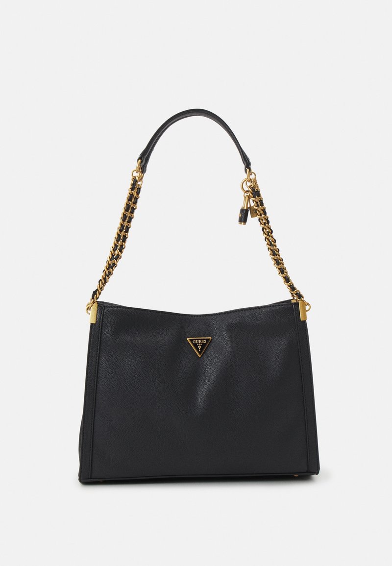 Sac à main en cuir noir avec bandoulière chaîne dorée, plaque triangulaire avec logo Guess et petit charm cadenas suspendu.