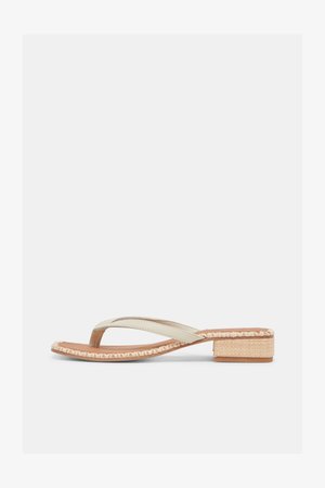 Beige sandal med lav hæl og vævet kant rundt om sålen samt en rem med tåadskillelse mod en hvid baggrund.