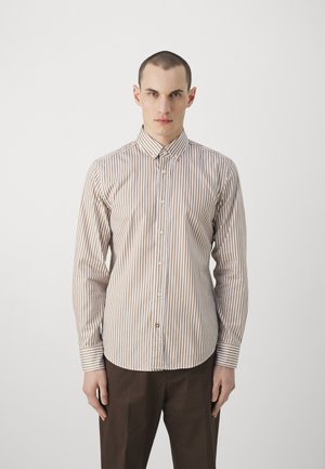 Camisa de botones a rayas en beige y marrón. Mangas largas, cuello clásico, con botones visibles y puños. Textura de tela suave.