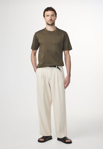 Olijfgroen katoenen t-shirt met een ronde hals, gedragen met hoogwaardige crèmekleurige broeken en zwarte slidesandalen. Eenvoudige, relaxte pasvorm.