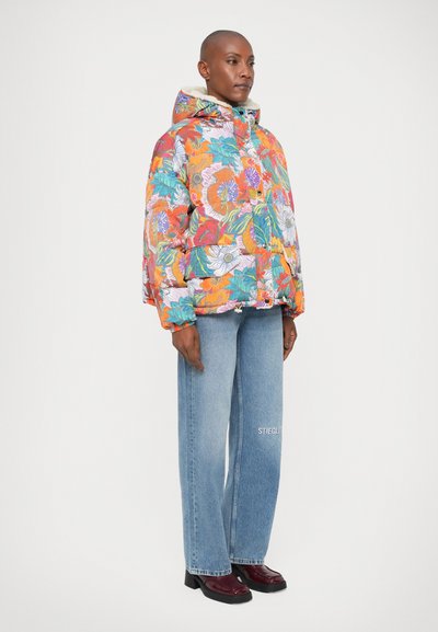 Farverig blomsterpufferjakke med hætte, der har et quiltet design, lynlås- og knaplukning, sat sammen med lyseblå straight-leg jeans.