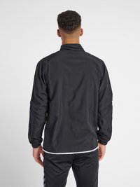 Schwarze leichte Jacke mit Stehkragen und langen Ärmeln, ausgestattet mit elastischen Bündchen und einem weißen Saum.