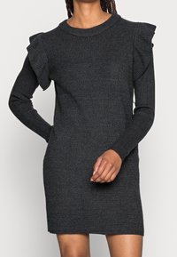 Vestito a coste grigio scuro con maniche lunghe, caratterizzato da accentuazioni arricciate sulle spalle e un collo rotondo. Il tessuto appare morbido e testurizzato.