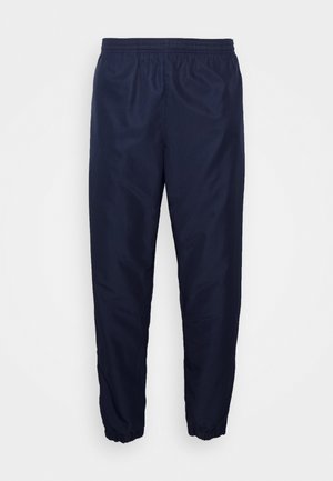 Pantaloni sportivi de culoare bleumarin, cu un tiv elastic, picioare conice și manșete. Realizați dintr-un material neted, ușor, cu un luciu subtil.