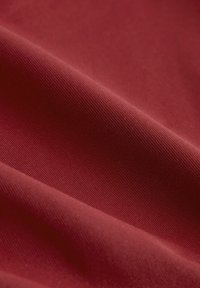 Hlboká červená látka s hladkou textúrou a jemným ribovaním, ktorá predvádza bohatú farbu a mäkký, pružný vzhľad.