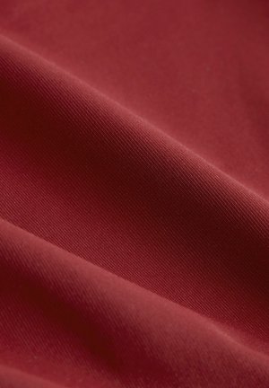 Sügavpunane kangas, millel on sile tekstuur ja õrn sooneline muster, esitleb rikkalikku värvi ja pehmet, paindlikku välimust.