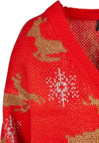 Pull en maille rouge avec motifs de rennes dorés et flocons de neige blancs, col en V et détails en fil métallique.