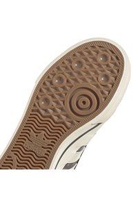 Guma podešev s texturovaným vzorem, který obsahuje kruhové a trojúhelníkové tvary. Barva je hnědá s krémovým okrajem a logem.