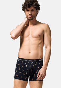 Czarne bokserki wykonane z bawełny z wzorem przedstawiającym butelki. Miękki pas z logo "LANČERTO". Model pozujący bez koszulki.