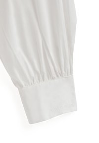 Camicia bianca a maniche lunghe con dettaglio arricciato sulle maniche e ricamo "POLO CLUB" sul polsino. Tessuto liscio e leggero con un taglio classico.