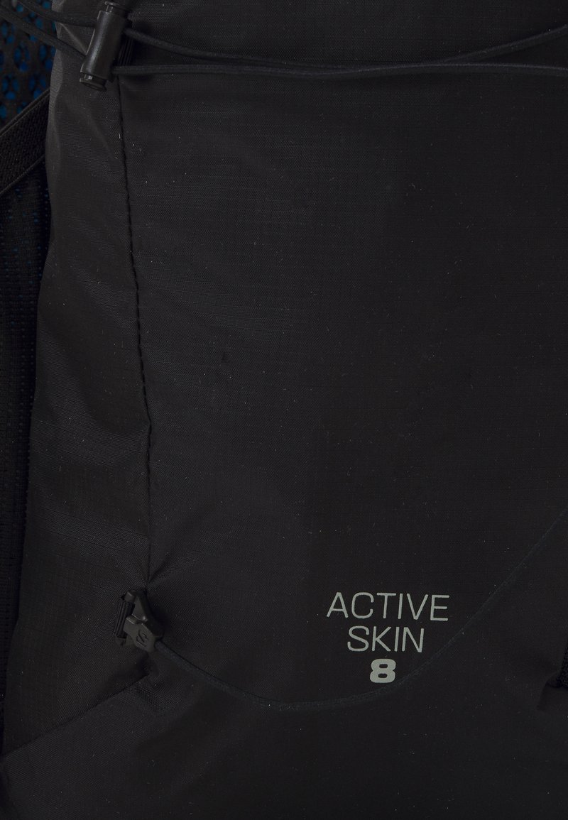 Zaino in tessuto nero con superficie testurizzata, dotato di un cordino regolabile, dettagli in rete e la scritta "ACTIVE SKIN 8".