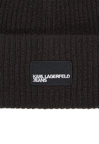 Tessuto a costine nero con etichetta nera rettangolare che mostra il testo bianco "KARL LAGERFELD JEANS".