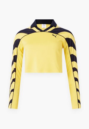Gul kortermet genser med lange ermer og svarte detaljer, polo-krage og en teksturert overflate med et dynamisk stripemønster. Puma-logo inkludert.