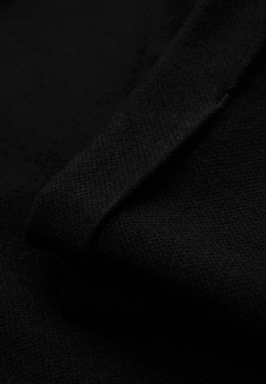 Zbliżenie na czarną teksturowaną tkaninę złożoną po skosie, podkreślającą jej drobny splot i miękką powierzchnię.