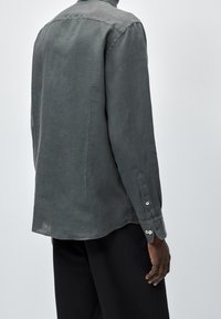 Long-sleeved shirt in dark grey linen, with a pointed collar and buttoned cuffs. Features a relaxed fit and subtle texture.