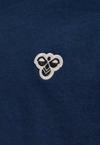 Tessuto di cotone blu navy con una consistenza morbida, caratterizzato da un logo ricamato bianco con accenti neri nella zona del petto.