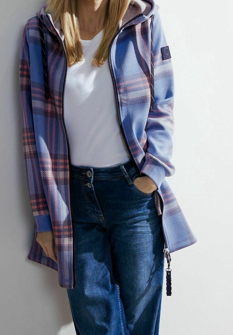 Giacca a quadri in tonalità blu e viola, con cappuccio, chiusura con zip e tasche. Abbinate a una maglietta bianca e jeans blu scuri.