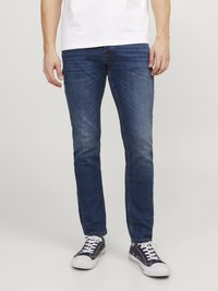 Blugi din denim de un albastru închis, cu o croială slim, design cu cinci buzunare și ușoară decolorare. Asortați cu adidași negri și albi.