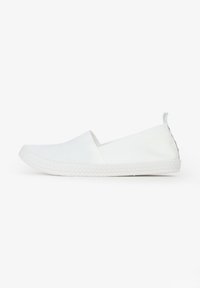 Scarpe slip-on bianche in tela con suola piatta in gomma testurizzata e inserti elastici laterali per un facile indossamento, caratterizzate da una parte superiore liscia e un design minimal.