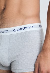 Szürke pamut boxer shorts, fehér derékrésszel, sötétkék "GANT" márkajelzéssel. Az anyag sima tapintású és jól illeszkedik.