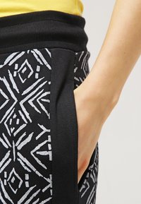 Zwarte joggers met een gepattern design in lichtgrijs, voorzien van een geribbelde tailleband en zijzakken.