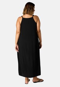 Schwarzes Maxikleid mit dünnen Trägern und weichem, strukturiertem Stoff. Verfügt über metallische Beschläge an den Schulterträgern und ein lockeres, fließendes Design.