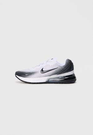 Weiße und schwarze Sportschuhe mit einem atmungsaktiven Mesh-Obermaterial, einer auffälligen Luftdämpfungseinheit und einem kontrastierenden gepunkteten Muster entlang der Ferse.