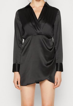 Robe chemise en satin noir avec des manches longues, un col, un design enroulé et une texture lisse. Présente des poignets en satin contrastants et un drapé latéral.