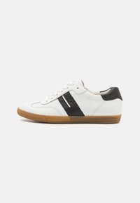 Sneaker in pelle bianca con accenti neri, punta rotonda, suola piatta in gomma, e chiusura con lacci. Presenta un design con pannello laterale testurizzato.