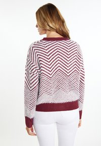 Pullover bordeaux e bianco a zigzag con finitura texturizzata, polsini e orlo a coste. Vestibilità comoda con scollatura rotonda.