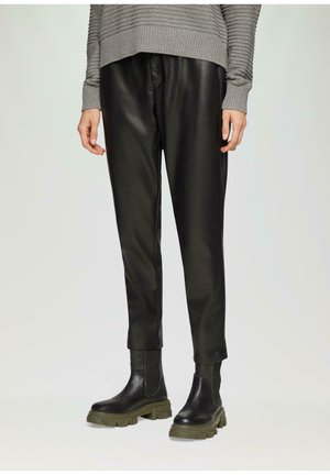 Zwarte neplederen broek met een gladde textuur, tapered design en boorden. Gepaard met chunky zwarte laarzen met olijfgroene zolen.