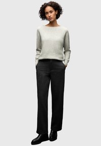 Light grey sweater with a wide neckline and long sleeves, paired with dark grey tailored pants. Smooth textures and straight cut. Black ankle boots.