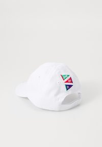 Balta medvilnės beisbolo kepurė su kreipiančiu kraštu. Savybė - trys spalvoti siuvinėti ženkliukai, ant kurių užrašyta "tiesiog", "daryk" ir "tai" įvairiomis spalvomis.