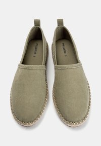 Baskets slip-on en toile verte avec une tige texturée, un bout rond et une semelle en jute cousue contrastante. Design simple et sans éléments de quincaillerie visibles.