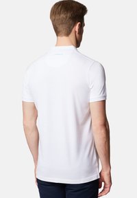 Biała koszulka polo z krótkim rękawem, gładką teksturą i dyskretnym logo na kołnierzyku. Luźny krój z prostym dołem.
