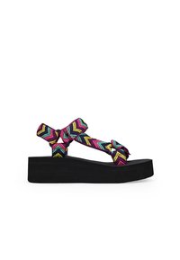 Sandalias de plataforma negras con una correa tejida colorida en un patrón de chevron en rosa, azul y amarillo; diseño anudado para un detalle adicional.
