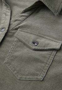 Camicia in corduroy verde oliva con colletto a punta, tasca frontale, chiusura con bottoni a pressione argentati e texture a righe verticali.