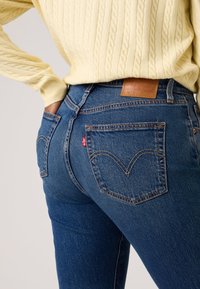 Μπλε τζιν από τζιν ύφασμα με εφαρμοστή σχεδίαση, κλασικό στιλ με πέντε τσέπες και χ αρακτηριστική λεπτομέρεια με ραμμένη τσέπη στο πίσω μέρος. Καφέ δερμάτινο λογότυπο μάρκας στη μέση.