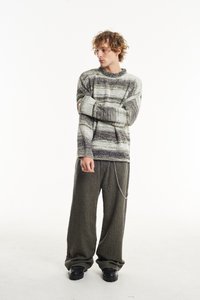 Purios pilkos ir baltos juostelės megztinis su apvaliu iškirpimu, derinamas su plačiausiais tamsiai žaliais kelnais ir juodais platforminiais batais.