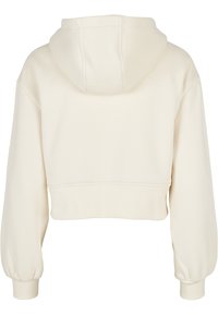 Sweat à capuche court couleur crème vu de dos avec manches longues, poignets ajustés et capuche.