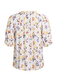 Blusa a maniche corte con sfondo bianco, decorata con motivi floreali multicolori in giallo, viola e rosa. Scollo e maniche volant.