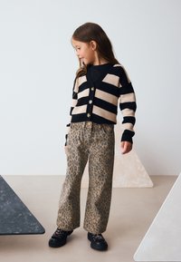 Sort og beige striped cardigan med knapper, kombineret med vidde ben leopard print bukser. Sorte sko fuldender outfittet.