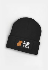 Black knit beanie featuring a square patch with a cartoon capybara and the text "STAY CHILL" in white bold letters.