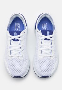 Scarpe sportive bianche con tomaia in mesh, dettagli blu sulla lingua e sulla suola, e lacci piatti. Presentano motivi testurizzati per la traspirabilità.