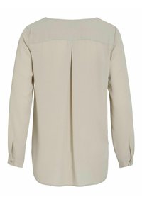 Blouse beige à manches longues avec empiècement au dos et pli central, poignets boutonnés et ourlet légèrement arrondi.